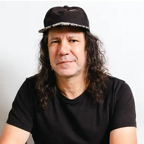 Portrait of Archie Moore, an Aboriginal man with long, curly dark hair wearing a black cap and black t-shirt.jpg