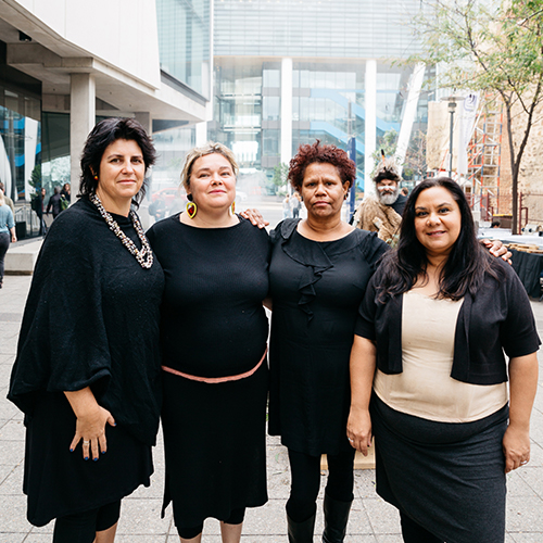 Portrait of the Unbound Collective. Four aboriginal women wearing black clothing stand with their arms around each other.jpg